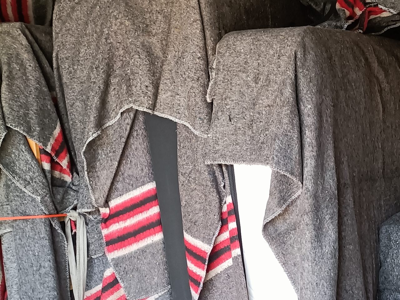 Blanket-protected furniture with a load restraint inside a moving truck.